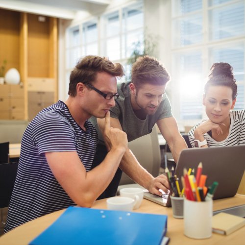 Group of graphic designers discussing over laptop at their desk in the office